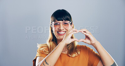 Buy stock photo Happy woman, portrait and heart hands with glasses for love, care or romance on a gray studio background. Face, female person or romantic gesture with smile, icon or emoji for support on mockup space