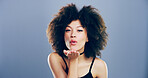 Portrait, happy woman and blowing kiss with love for romance, affection or greeting on a gray studio background. Creative, female person or model with afro, care or palm for flirt on mockup space
