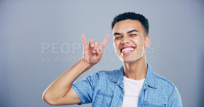 Buy stock photo Rock, smile or portrait of man with hand gesture in studio space for wild expression on gray background. Culture, edgy male rocker and crazy person with devil horn sign, funky emoji and punk symbol