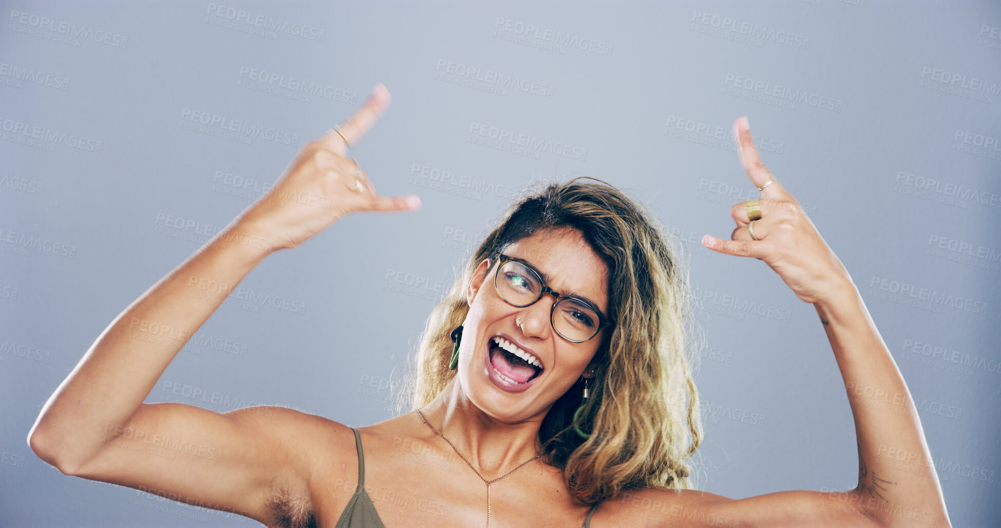 Buy stock photo Portrait, wild and woman with rock hand gesture in studio, expression or space on gray background. Glasses, edgy female rocker and crazy model with devil horn sign, funky emoji or punk culture symbol