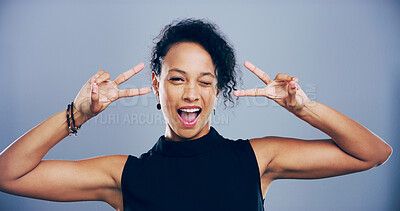 Buy stock photo Studio, woman and portrait with wink for peace sign, support and motivation for silly feedback. Goofy expression, female person and model with hand gesture for v symbol, good mood by gray background