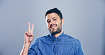 Portrait, creative and happy man with peace sign in studio with positive attitude, confidence or facial expression. Grey background, casual and proud male model for cool gesture, fashion or v symbol 