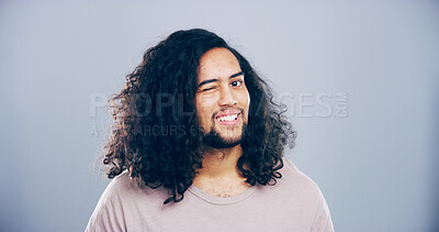 Buy stock photo Man, happy and face with wink in studio portrait, sign or emoji for secret, flirt and joke by gray background. Person, model or smile with gesture, playful and eye symbol by space in New Zealand