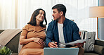 Pregnant woman, man and worry with finance in home on sofa with documents, debt and laptop in lounge. Couple, parents and stress for crisis, bankruptcy and discussion with budget, payment or bills