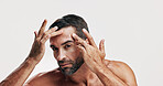 Studio, portrait and man check skincare for dermatology routine, self care or glow on white background. Natural, facial treatment and male model with cosmetics, face inspection or grooming for beauty