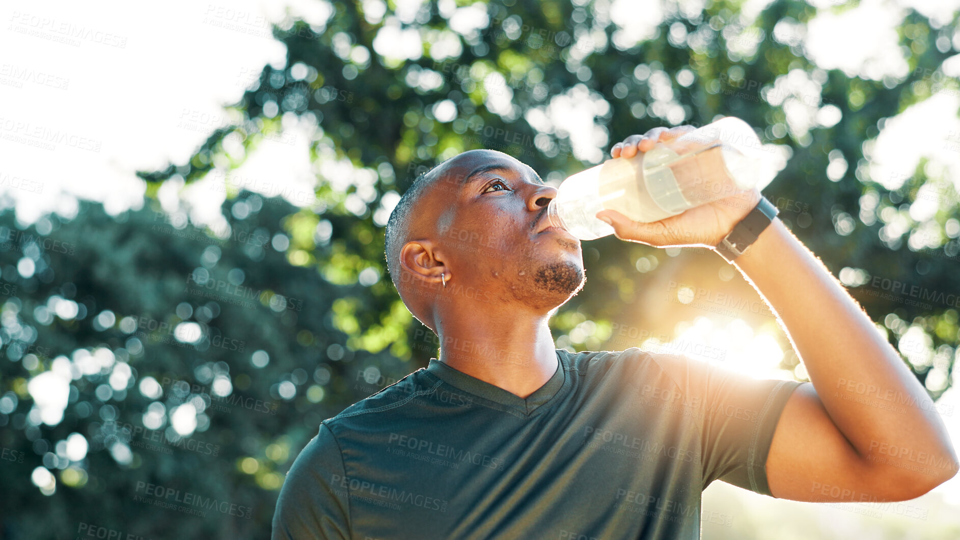 Buy stock photo Fitness, black man and drinking water outdoor for health, wellness and exercise recovery. Bottle, thirsty athlete and hydration at park for electrolytes, nutrition and detox in low angle on break