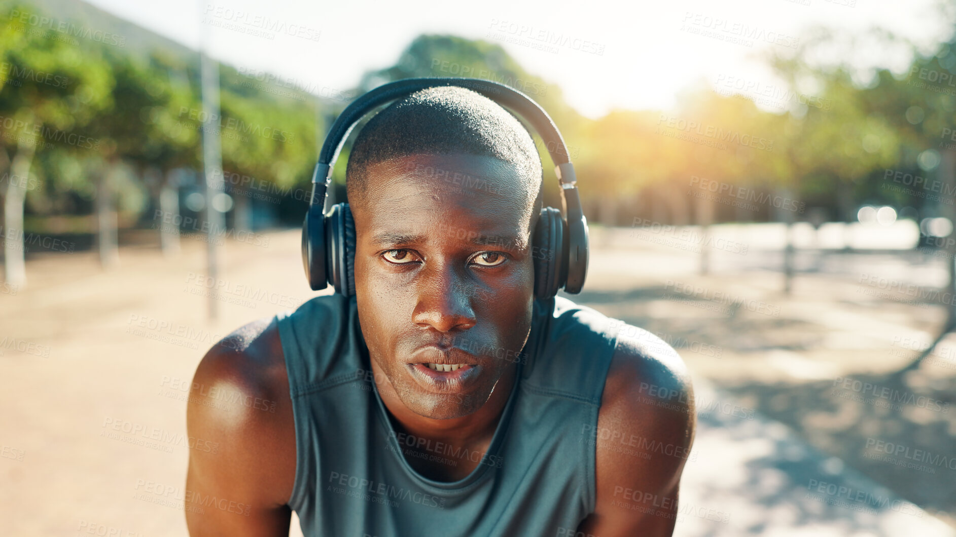 Buy stock photo Fitness, break and black man with headphones outdoor for workout music, cardio challenge or running performance. Athlete, portrait and tired in nature with sweating, rest or training recovery at park