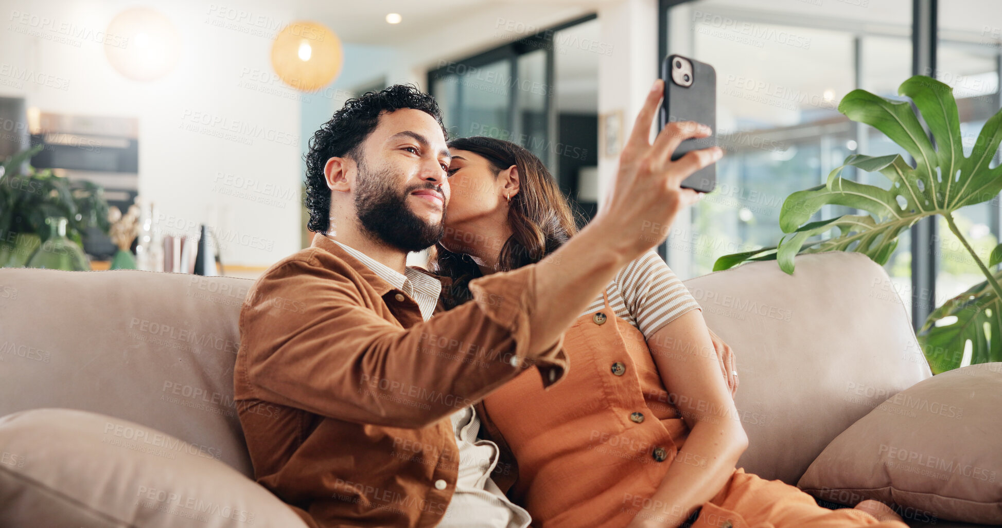 Buy stock photo Selfie, kiss and couple in home, relax and post for memory in social media, bonding and chilling. Embrace, man and woman with picture, photography and break in living room with spouse, love or house