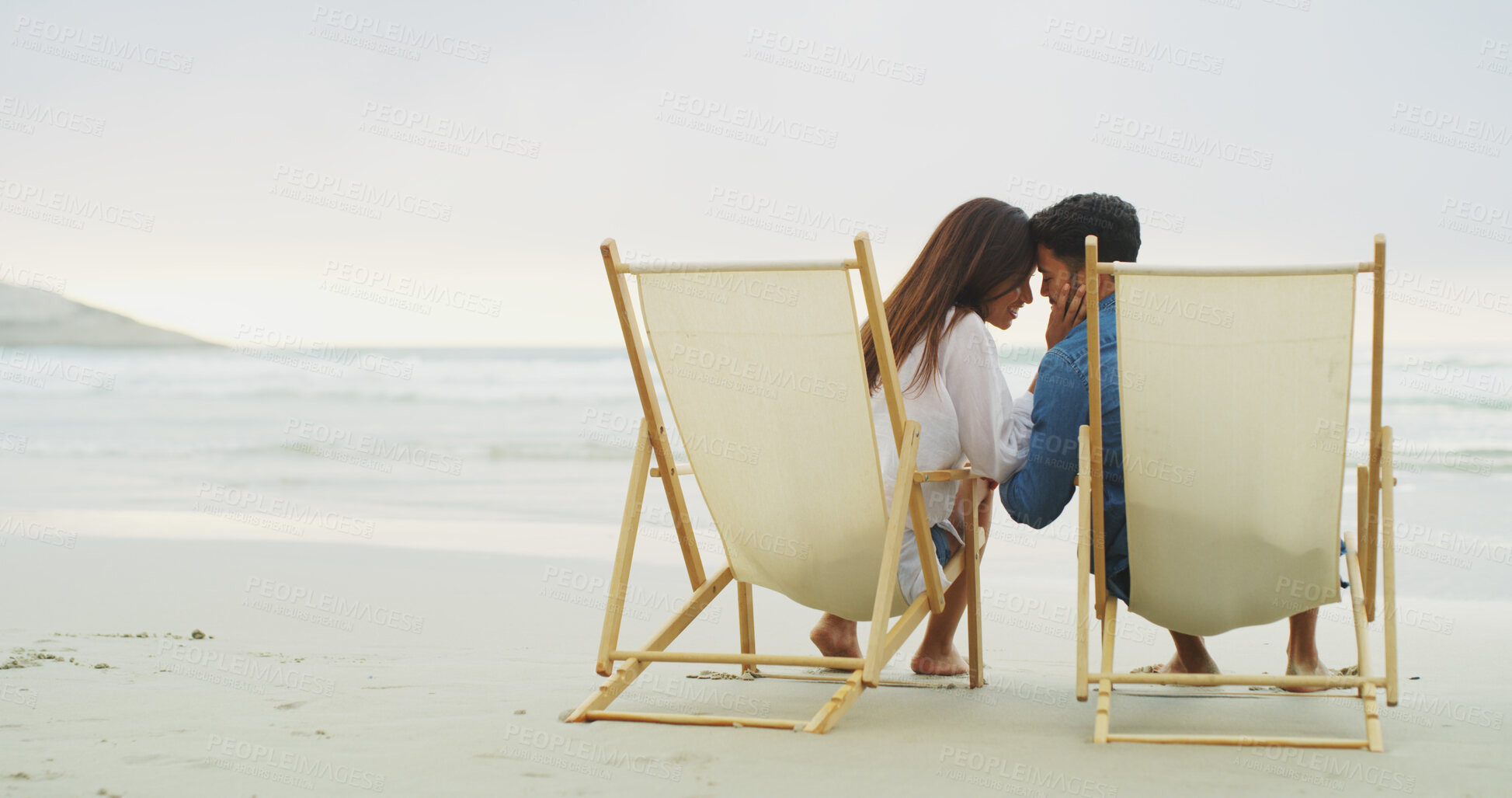 Buy stock photo Beach chair, couple and relax on vacation for honeymoon, holiday or bonding outdoor. Woman, man and relationship by sea for space, romantic date and care with forehead touch for connection in nature