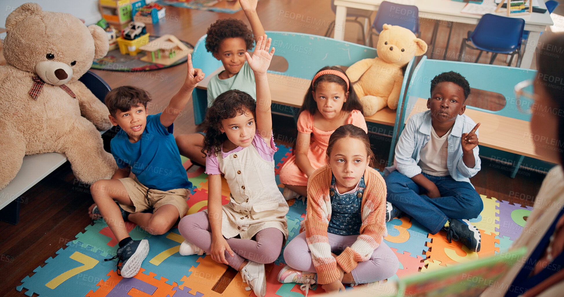 Buy stock photo Lesson, children and hands raised with answer in classroom for reading questions, knowledge and story feedback. Teacher, book and students on floor for learning development, language quiz and above