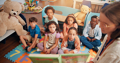 Buy stock photo Reading book, classroom and children listening to teacher for lesson, education and learning. Preschool, students and kids on floor with educator for storytelling, language development and knowledge