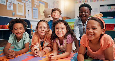 Buy stock photo Children, group and smile on floor in classroom, portrait and excited with diversity, education and scholarship. School kids, happy and lying on mat with friends, solidarity and learning at academy