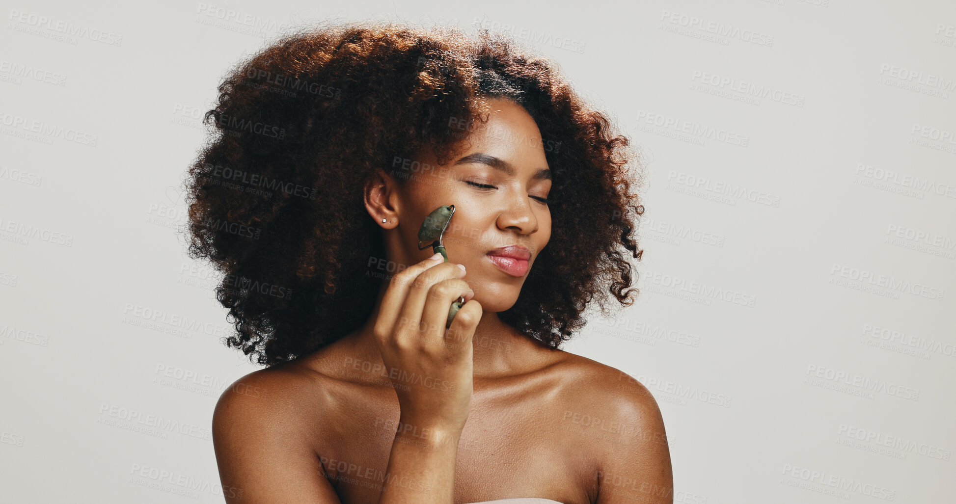 Buy stock photo Beauty, skincare and woman with jade roller in studio for skin glow, lymphatic drainage and detox circulation. African model, cosmetics tool and massage face for dermatology on white background space