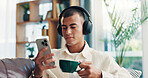 Home, man and coffee with mobile for music, wellness and comfortable on sofa in morning. House, male person and relax with headphones for listening sound, espresso and smartphone app for audio track