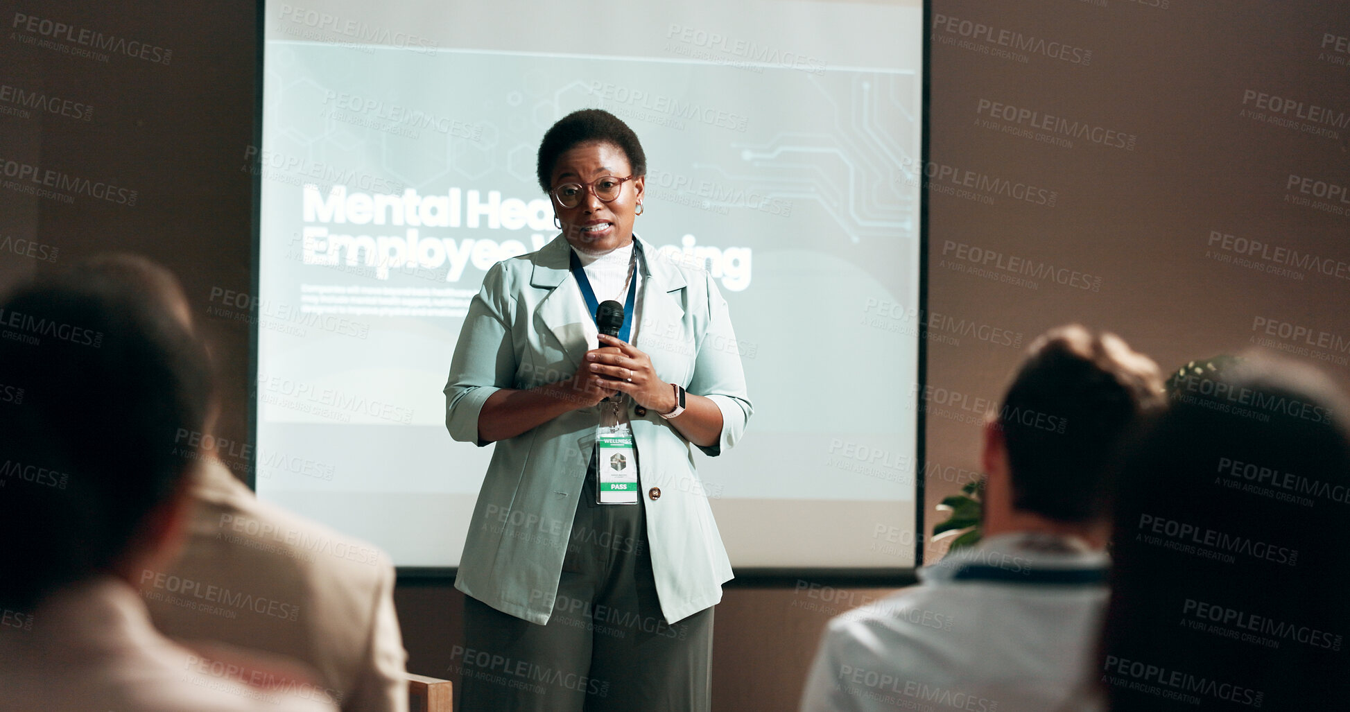 Buy stock photo Seminar, speaker and woman with mic, talking and public speaking for mental health in workplace or stage. Business, presentation and employee with speech for audience, people and podium for presenter