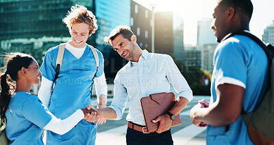 Buy stock photo Shaking hands, city and professor with medical students for support, greeting or congratulations. Happy, meeting and lecturer with healthcare interns for exam review with handshake in urban town. 