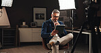 Talk show presenter, man and thinking with tablet in home studio for live streaming, online interview or podcast. Filming set, lights and mature journalist with digital script for broadcast research
