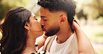 Hug, kiss and couple on date, outdoor and romance for people in nature, commitment and anniversary. Park, woman and affection for man, embrace and together for valentines day, care or relationship
