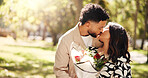 Kiss, gift and couple with flowers, outdoor and celebration for anniversary for people and romance. Love, man and present for woman with bouquet, affection and bonding with commitment to relationship 