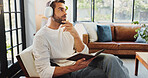 Thinking, man and headphones in home for notebook, writing thoughts and personal reflection with music. Sofa, male person and ideas with audio track for journal, diary and to do list in living room