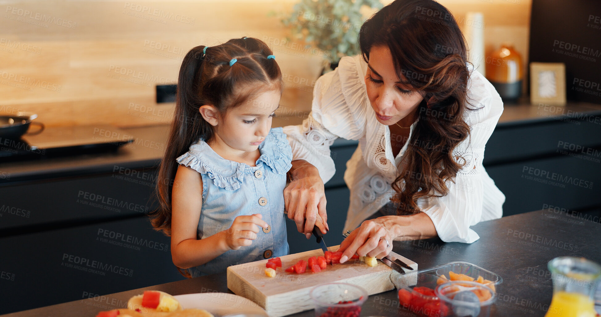 Buy stock photo Mom, girl and help in kitchen with fruit salad, cutting board and learning for nutrition in home. Teaching, mother and daughter with snack, food and meal for cooking, diet or bonding in family house