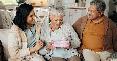 Buy stock photo Birthday, present or retirement with family on sofa in living room of home together for bonding or celebration. Box, gift or love with senior parents and daughter in apartment for event or milestone