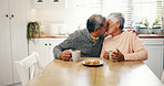Hug, kiss and senior couple with coffee, home and bonding with beverage in kitchen and elderly people. Happy, old man and mature woman with tea in house, comfortable and embrace for love in morning