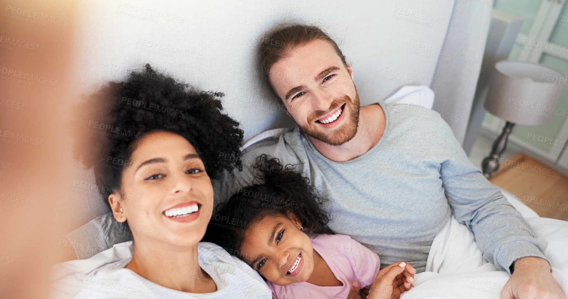 Buy stock photo Parents, girl and selfie in bed, smile and portrait with care, memory and post on web in morning at house. Man, woman and happy with photography, bonding and social media in interracial family home