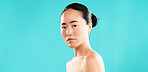 Portrait, skincare and Asian woman with cosmetics, dermatology and glow on blue studio background. Japanese person, confidence and model with healthy skin, shine and grooming with mockup space