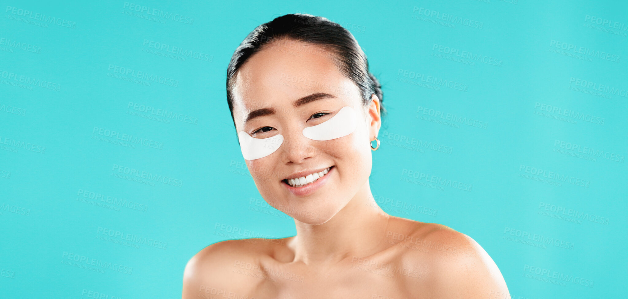 Buy stock photo Studio, Asian woman and skincare with eye patches in portrait, facial treatment or collagen with smile. Happy, female person and model with skin gel for beauty, cosmetics or mockup by blue background