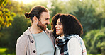 Love, happy and couple hug in park for support, trust and relax together outdoors in morning. Interracial, nature and man and woman laugh for conversation embrace for bonding, relationship or romance