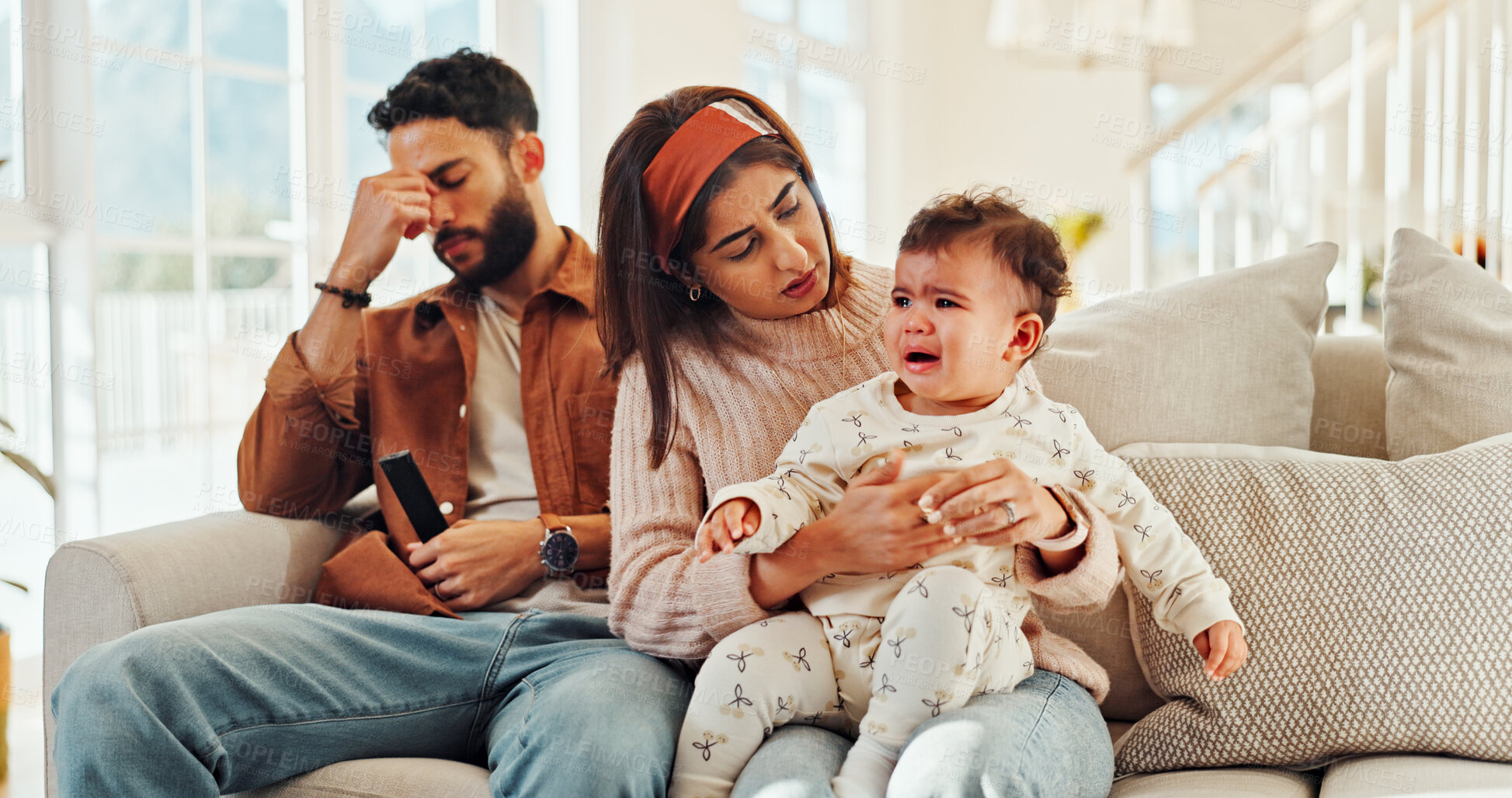 Buy stock photo Family, man and woman with baby, crying and stress for new parents with child, lounge and home. Noise, father and annoyed by interruption from game, thinking or mother with emotional toddler in house