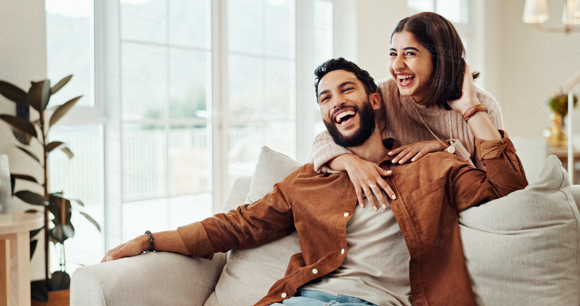 Buy stock photo Hug, happy and couple in home, bonding and relax in living room with smile, man and woman on break. Embrace, comfortable and people in relationship on couch, laughing and conversation, chat or house
