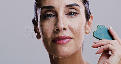 Buy stock photo Facial massage, portrait and skincare with woman in studio for antiaging cosmetics or dermatology. Beauty, gua sha and jade with person isolated on gray background for crystal stone face treatment