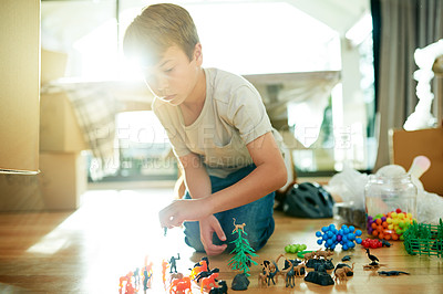 Buy stock photo Boxes, moving and child with toys in new home for fun, development or growth with youth. Entertainment, cardboard and boy kid playing with plastic trinkets for game in family house for relocation.