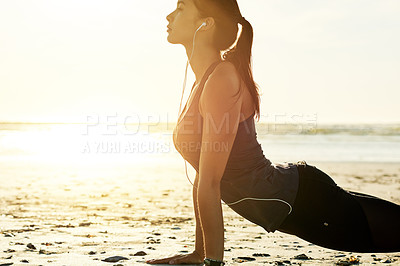 Buy stock photo Exercise, yoga and woman at beach in cobra pose for posture, wellness or holistic health for calm. Music, earphones or zen person stretching spine for mindfulness audio, chakra balance or awareness