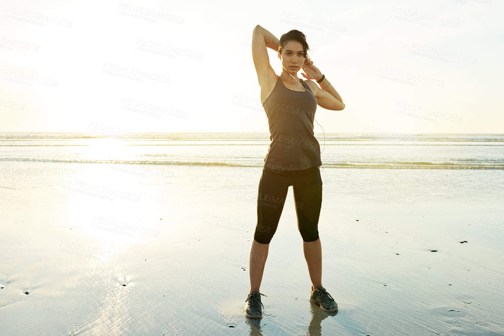 Buy stock photo Girl, stretching and earphones by ocean, sunset and ready for training in summer with streaming. Person, woman and workout with warmup, subscription and listen to music for fitness at beach in Spain