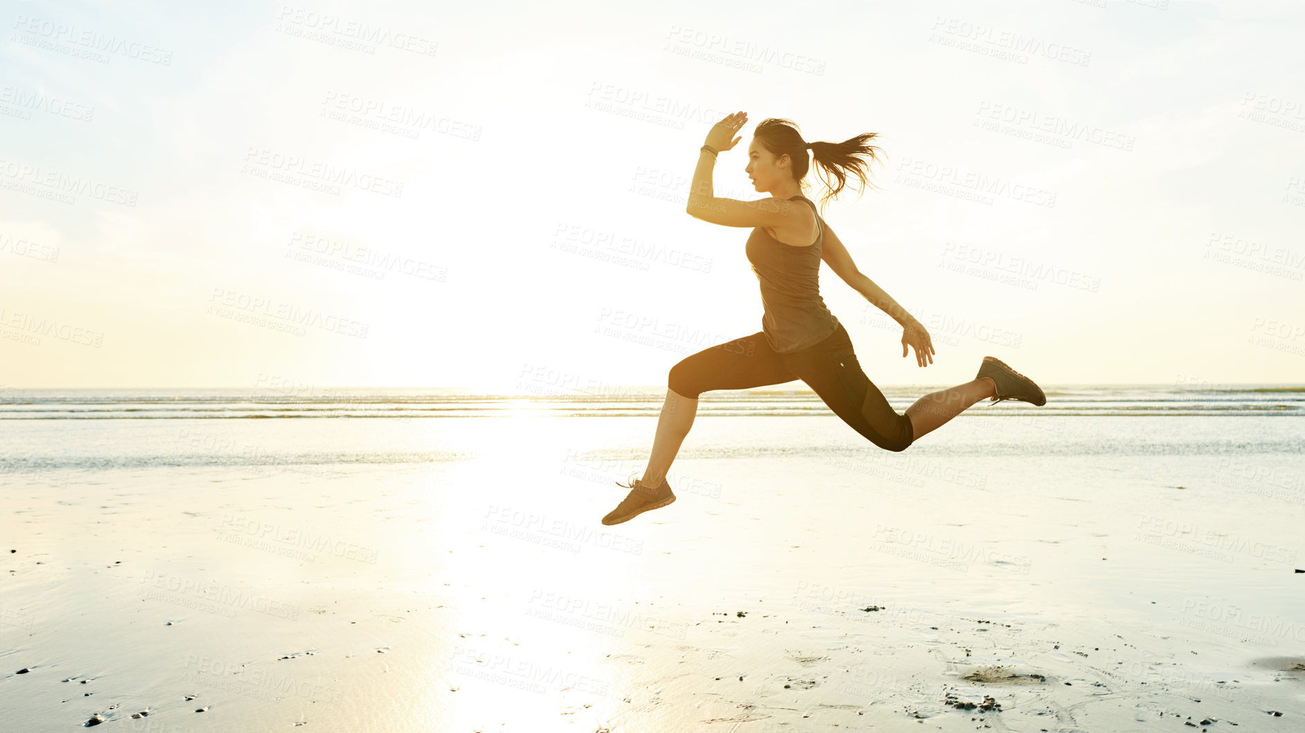 Buy stock photo Woman, running and jumping for fitness at beach with energy, exercise and cardio training. Female athlete, air and runner with marathon performance of sports race, speed workout and competition goals