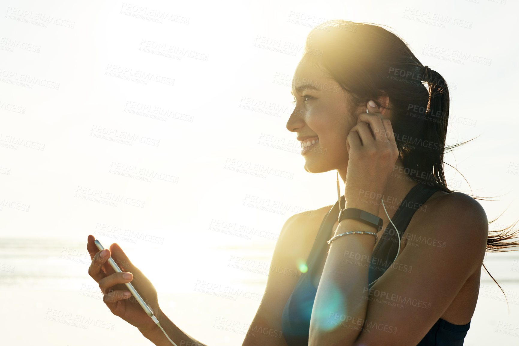 Buy stock photo Woman, mobile and music on beach for fitness, streaming service and exercise tutorial. Athlete, phone and earphones with sky space for motivational podcast, workout playlist and wellness tracking app