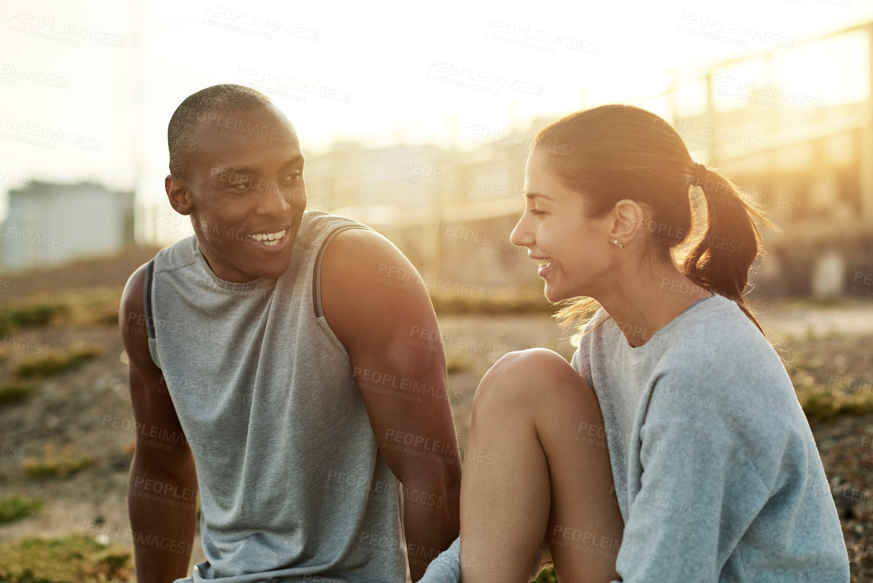 Buy stock photo Outdoor, couple and break with talking for fitness, wellness and bonding with smile for exercise. City, woman and man with support for training rest, conversation and healthy relationship by flare
