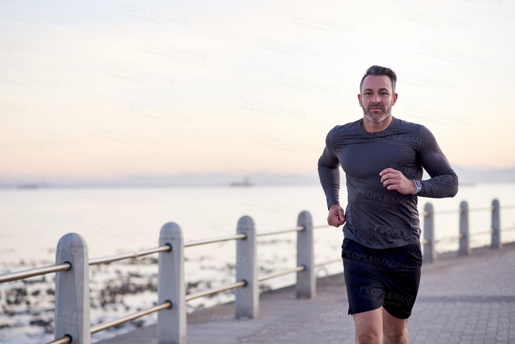 Buy stock photo Seaside, running and man with fitness, training and wellness with workout, exercise and routine. Person, athlete and runner with performance, ocean and sports with body health, challenge and cardio