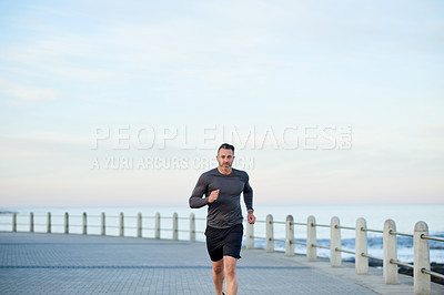 Buy stock photo Seaside, running and man with sports, training and wellness with workout, energy and practice. Person, athlete and runner with endurance, exercise and routine with body health, challenge and cardio
