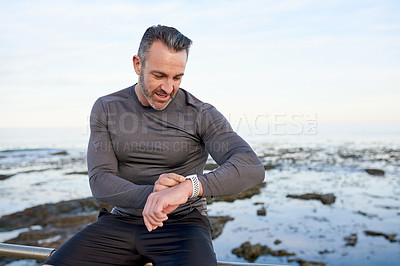 Buy stock photo Man, smart watch and fitness on promenade ocean by app, break or check stats for workout in morning. Mature person, training and runner by sea with iot, stopwatch or progress with exercise in Spain