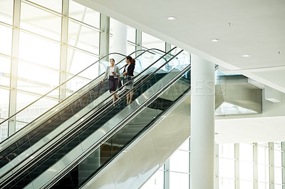 Buy stock photo Business, women or travel on escalator in office for meeting commute, work arrival or career discussion. Professional, people or talking on moving staircase for corporate journey or seminar departure