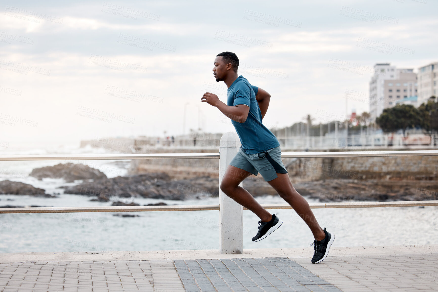 Buy stock photo Black man, runner and exercise outdoor on beach promenade for fitness, training or cardio workout. African athlete, person and running at sea for performance, health and wellness in nature with focus