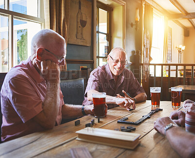 Buy stock photo Group of senior men sitting together and playing dominoes in a bar, bonding, strategy game, senior friends enjoying a game of dominoes in a pub