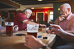 Group of senior men sitting together and playing dominoes in a bar, bonding, strategy game, senior friends enjoying a game of dominoes in a pub