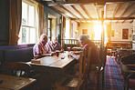 Group of senior men sitting together and playing dominoes in a bar, bonding, strategy game, senior friends enjoying a game of dominoes in a pub