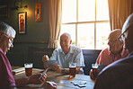 Group of senior men sitting together and playing card games in a bar, bonding, senior friends enjoying a game of bridge in a pub