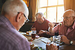 Senior man sitting with friends and enjoying lunch in a bar. Elderly men bonding eating lunch in a pub, senior friends